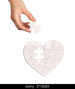 Adding last puzzle piece to complete jigsaw, love heart Stock Photo