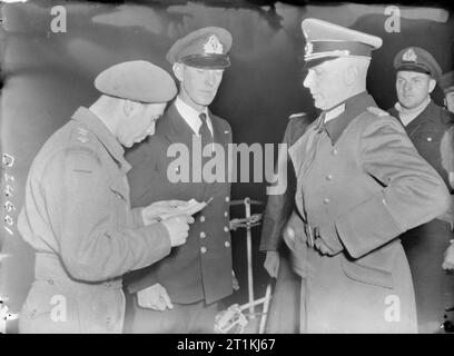 Channel Islands Liberated- the End of German Occupation, Channel Islands, UK, 1945 Major General Heine, German Commander-in-Chief of the Channel Islands (right), has his identification papers checked as arrives at HMS BULLDOG to sign the document of surrender. Stock Photo