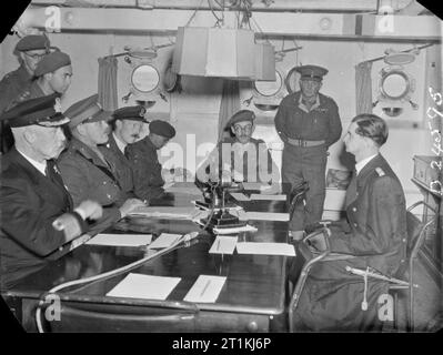 Channel Islands Liberated- the End of German Occupation, Channel Islands, UK, 1945 A scene on board HMS BULLDOG during the first conference with Captain Lieutenant Zimmerman prior to the signing of the surrender document which liberated the Channel Islands. Left to right around the table are: Admiral Stuart (Royal Navy), Brigadier General A E Snow (Chief British Emissary), Captain H Herzmark (Intelligence Corps), Wing Commander Archie Steward (Royal Air Force), Lieutenant Colonel E A Stoneman, Major John Margeson, Colonel H R Power (all of the British Army) and Captain Lieutenant Zimmerman (Ge Stock Photo