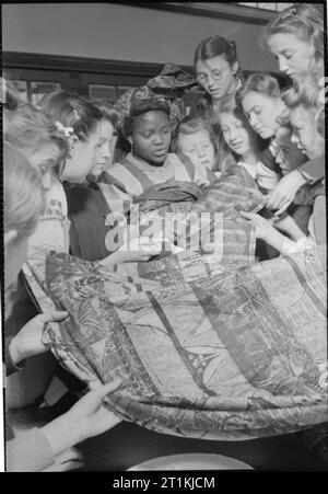 Colonial Students in Great Britain- Students at University of London Institute of Education, London, England, UK, 1946 Miss E A Adebonojo (from Ode, Ijebu country, Yoruba Land, Western Nigeria) shows large pieces of traditional handwoven cloth to pupils at Marlborough Senior Girls School, Isleworth. She is wearing a traditional Nigeria headdress. According to the original caption, Miss Adebonojo has taken teacher training at the United Missionary College, Ibadan, and has taught at a girls' boarding school. She has won the Nigerian Teacher's Higher Elementary Certificate and is taking a year's Stock Photo