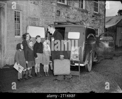 Film Show at Highest Village in the Highlands- Ministry of Information Film Screening, Tomintoul, Banffshire, Scotland, UK, 1943 A group of local children look on as Ministry of Information Film Operator John Macdougall arrives outside the Memorial Hall in Tomintoul to set up his film equipment. He is unloading his van as he prepares to transform the village hall into a cinema for the evening. The film is due to start at 8pm. Stock Photo