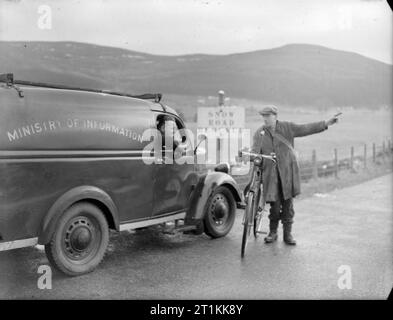 Film Show at Highest Village in the Highlands- Ministry of Information Film Screening, Tomintoul, Banffshire, Scotland, UK, 1943 Ministry of Information Film Operator John Macdougall stops to chat to a local with a bicycle on his way to Tomintoul, a small village 1200ft up in the Cairngorms. The road ahead is blocked by snow, and the local is advising John on the best way to drive his Ministry of Information van to the village. John is on his way to the Memorial Hall to run a film show which is due to begin at 8pm. Stock Photo