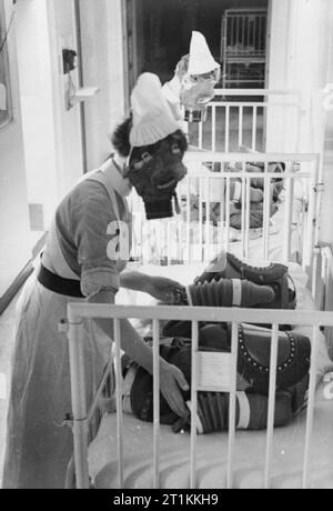 Gas Drill at a London Hospital- Gas Masks For Babies Are Tested, England, 1940 Two nurses each pump the bellows of a baby gas respirator in order to supply the child wearing the mask with air, during a gas drill at a London hospital, 1940. Stock Photo