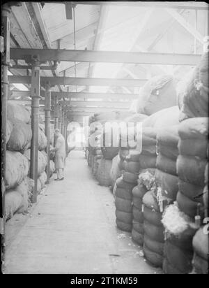 Huddersfield Cloth Mill- the work of C and J Hirst and Sons Ltd., Sunnybank, Longwood, Huddersfield, Yorkshire, England, UK, 1943 A view of large bales of wool stored in the warehouse of C and J Hirst and Sons Ltd., at Sunnybank in Longwood, Huddersfield. A mill worker can be seen checking this raw material in the distance. Stock Photo