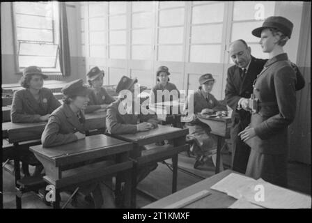 London Buses in Wartime, England, 1941 Examination day at the bus conductors' training centre. Prospective conductors are trained on the road and then return to the classroom for their final test. Here we see the instructor demonstrating the ticket punch with the use of a conductor mannequin. This photograph was probably taken in September 1941. Stock Photo