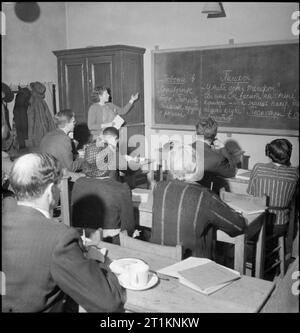 Morley College in Wartime- Everyday Life at Morley College, Westminster Bridge Road, London, England, UK, 1944 Students of all ages sit at rows of desks to during a lesson in Russian at Morley College. The lecturer is drawing the attention of the class to the sentences she has chalked on the blackboard. Stock Photo