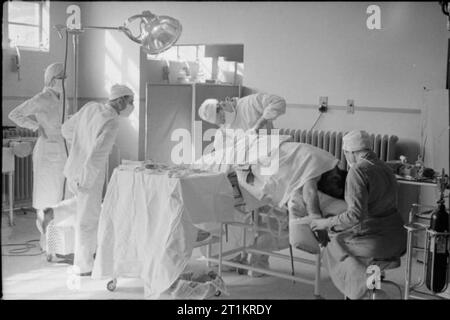 American Hospital in England, 1943 Surgeon Lieutenant Kenneth F Maclean operate on Private Louis Mercurio from New York in the operating theatre at the American Hospital. The anaesthetist is Miss Wooliver. Several other doctors watch the proceedings. Stock Photo