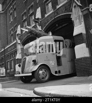 The Reconstruction of 'an Incident'- Civil Defence Training in Fulham, London, 1942 A fire engine leaves Fulham Fire Station on its way to the incident, elsewhere in the borough. The firemen put on their helmets and gas masks as they go. Fulham Fire Station is at 685 Fulham Road. Stock Photo