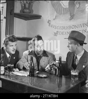 The Seven Seas Club- Life at the Merchant Navy Club, Edinburgh, Scotland, 1943 Werner Petersen (left) and Hans Christensen (right) from Denmark join Charles Andrade, an American Merchant Seamen from Honolulu, for a drink and a smoke in the bar of the Seven Seas Club in Edinburgh. Stock Photo