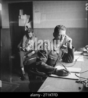 Americans in Britain- the work of No 121 (eagle) Squadron RAF, Rochford, Essex, August 1942 In the Dispersal Hut at Rochford airfield, the telephonist logs a call from the Control Tower, confirming that 12 Spitfires are successfully airborne. In the background, a 'spare' pilot reads a book. Stock Photo