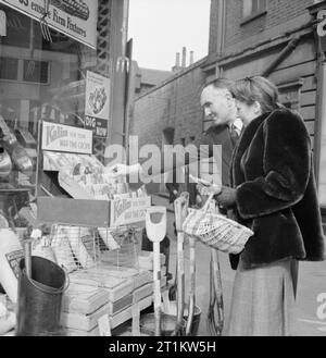War Bride- Everyday Life in Wartime London, March 1943 Newly-engaged Marcelle Lestrange buys vegetable seeds from a salesman in London. Civilians are encouraged, through the 'Dig for Victory' campaign, to grow their own vegetables anywhere they can, so even if they do not have a garden, a window box should be used instead. Stock Photo
