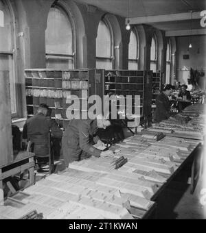 Army Post Office in the Midlands, England, 1944 Staff at the Army Post Office 'somewhere in the Midlands' work on the card index of two million casualties that is maintained there. This index enabled letters for prisoners to be sent to the Red Cross for delivery, and enabled letters for wounded service personnel to be sent to the correct hospital. It also meant that the next-of-kin of the dead could have their letters returned to them after they had received their official War Office notification. In the background, more staff can be seen sorting mail. Stock Photo