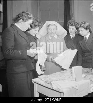 Wrens Learn Mothercraft- Members of the Women's Royal Naval Service Receive Training From the Mothercraft Training Society, London, England, UK, 1945 Matron Miss Maslen-Jones shows baby clothes to a group of Wrens as part of the training they are receiving from the Mothercraft Training Society, probably at the MTS headquarters in Highgate, London. According to the original caption, these clothes were made by nurse trainees. 'These garments are designed with a view to economy of material but with due consideration to health and wellbeing'. Stock Photo