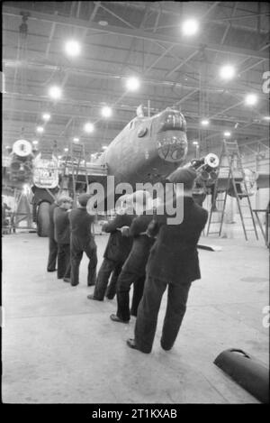 Birth of a Bomber- Aircraft Production in Britain, 1942 A team of men haul the engines of this Halifax into position at the Handley Page factory in Cricklewood. Stock Photo