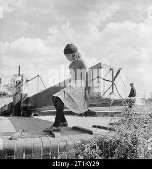 British Canals in Wartime- Transport in Britain, 1944 Valerie Gribbis, daughter of a canal boatman, opens the top gates of a lock, somewhere along the Grand Union Canal. Stock Photo