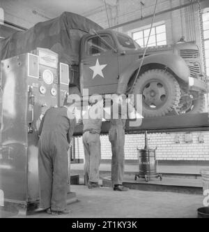 British Goods in US Marshalling Yards- Anglo-american Co-operation in Wartime Britain, 1943 Corporal Clarence Whittington from Annapolis, Maryland, USA, and 17 year old Bob Whiting from Tewkesbury, Gloucestershire, at work on an American lorry at a US marshalling yard, somewhere in Britain. In the foreground, another British worker can be seen. Stock Photo