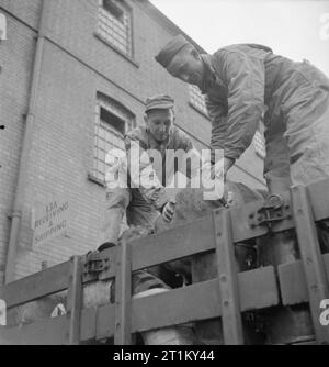 British Goods in US Marshalling Yards- Anglo-american Co-operation in Wartime Britain, 1943 Pfc Walter Toye (left) of 4609 Hedge Street, Philadelphia and Pfc Francis P Owen, of Port Tobago, Maryland, load a bale of cotton waste onto a lorry at a US marshalling yard, somewhere in Britain. The lorry is just about to set off to a neighbouring unit with a week's supply of goods. Stock Photo