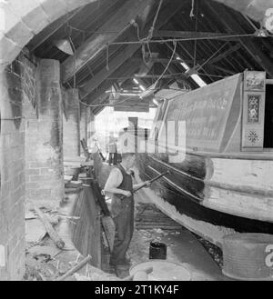 British Canals in Wartime- Transport in Britain, 1944 A canal boat of the Samuel Barlow Coal Co. Ltd. is tarred in the dry dock of Nurser's yard at Braunston, Northamptonshire. Braunston lies at the junction of the Grand Union Canal and the Oxford Canal. Stock Photo