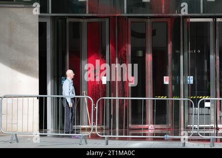 London, UK. 14 October, 2023. A member of staff inspects the BBC HQ entrance after it was earlier defaced with red paint, reportedly in protest at the broadcaster's coverage of Israel's war on Gaza. Credit: Ron Fassbender/Alamy Live News Stock Photo