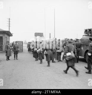 The Liberation of Bergen-belsen Concentration Camp, April 1945 The British Army arrives at Belsen concentration camp. German and Hungarian guards stand at the camp entrance as German Wehrmacht troops (wearing white armbands) enter the camp under the truce agreement reached with the British on 12 April 1945. On the right is a vehicle equipped with loudspeakers from 14 Amplifier Unit, Intelligence Corps under the command of Lt Derrick Sington (Q103469181). This vehicle, accompanied by vehicles of 63rd Anti Tank Regiment, Royal Artillery, was the first to enter the camp and was used to inform the Stock Photo