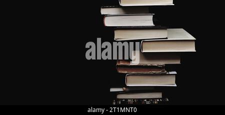 Composition of piled up books on a black background. Minimal corner composition. Copy space. Educational concept Stock Photo