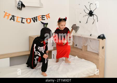 Children in skeleton and witch costume laughing at home halloween Stock Photo