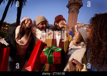 Excited smiling group multi-ethnic people holding colorful shopping bags gifts. Laughing young. Stock Photo