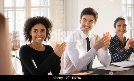 Happy motivated young diverse business team applauding speaker after presentation Stock Photo