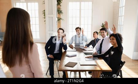 Happy diverse business team voting on presentation, raising hands Stock Photo