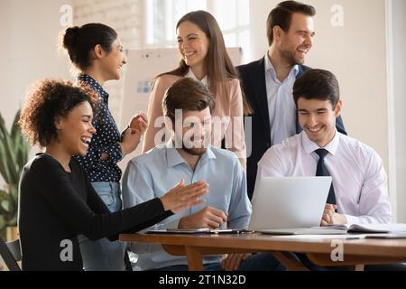 Cheerful diverse coworkers enjoying teamwork success, successful cooperation Stock Photo