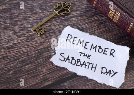 Remember Sabbath Day, handwritten Christian text with holy bible and antique key on wooden table. Obedience, worship, rest on the seventh day concept. Stock Photo