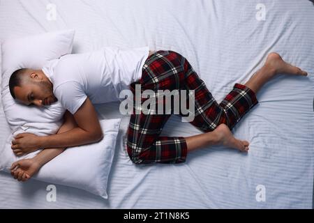 Man suffering from insomnia on bed, top view Stock Photo