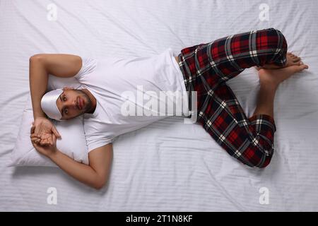 Man suffering from insomnia on bed, top view Stock Photo