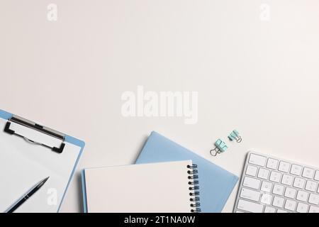 Flat lay composition with computer keyboard and different stationery on white desk, space for text. Home office Stock Photo