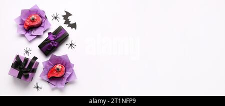 Delicious cakes, gift boxes and Halloween decorations on white background with space for text, top view Stock Photo