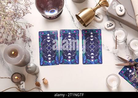 Witch's magic attributes with tarot cards on light background, closeup ...