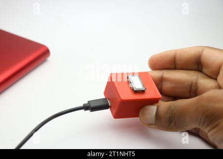 Small bluetooth speaker made from 3d printed parts and a mini bass speaker is put for charge using USB cable held in the hand Stock Photo