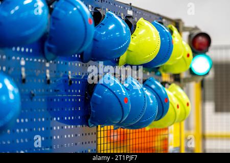 safety helmets of different colors on a rack in a factory, the concept of safety against injuries at work and health protection Stock Photo