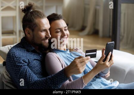 Young married couple using smartphone and credit card Stock Photo