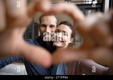 Happy dating couple in love making finger heart shaped frame Stock Photo