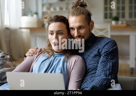 Shocked happy couple getting email message with surprising good news Stock Photo