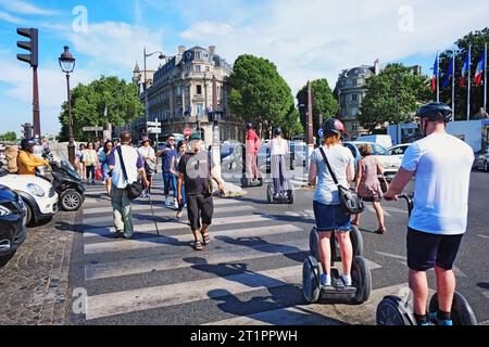 A busy zebra crossing in Paris with a Paris Segway tour and pedestrians, cars lined up ready to rush forward Stock Photo