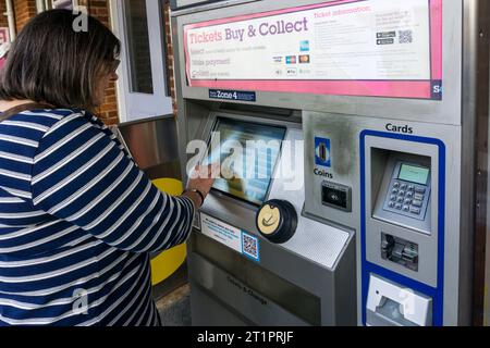 Woman buying railway tickets from a Southeastern railway ticket machine outside Shortlands station in south London. Stock Photo