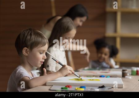 Pretty pupil boy painting during group class Stock Photo