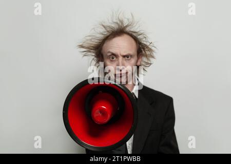 Red loudspeaker in hand of funny businessman on white background Stock Photo