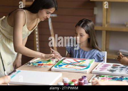 Artist woman teaching little girl during art class in studio Stock Photo