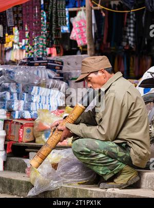 Vietnamese man at Can Cau market smoking from a bamboo water bong Stock ...