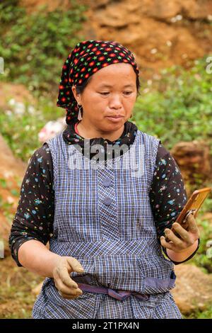 Can Cau Market Scene, Vietnam. Hmong Woman Checking her Cell Phone, Lao Cai Province. Stock Photo