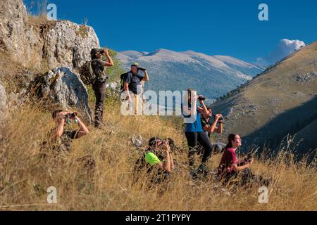 Bisegna (AQ), Italy - October 8, 2023: Group of hikers in the mountains observes wild animals in nature with binoculars. Stock Photo
