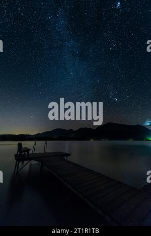 Wooden jetty on the shore of Lake Kochel in the Bavarian mountains under a starry night sky, Germany Stock Photo